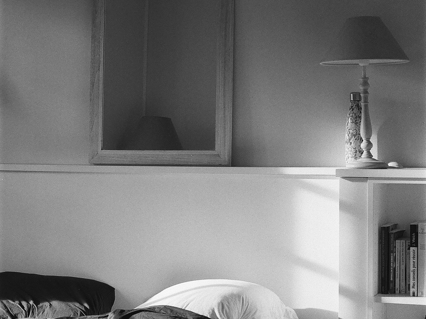 A bed in a bedroom, in black and white.