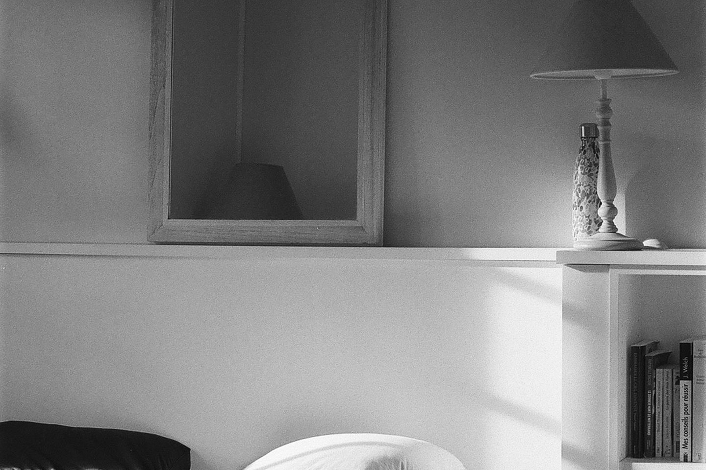 A bed in a bedroom, in black and white.