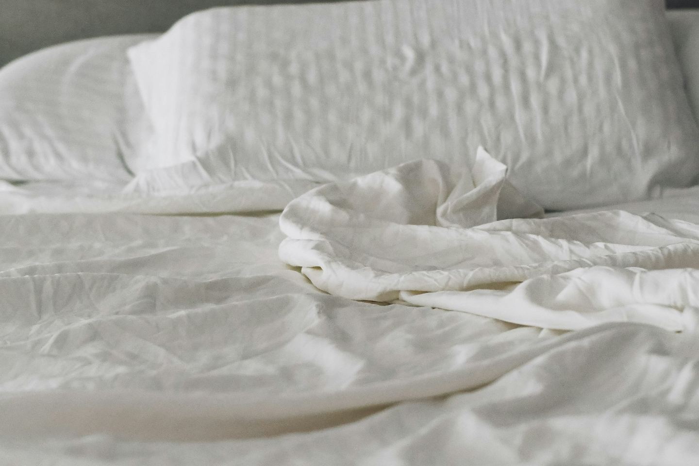A neatly made bed with white linen and two pillows.