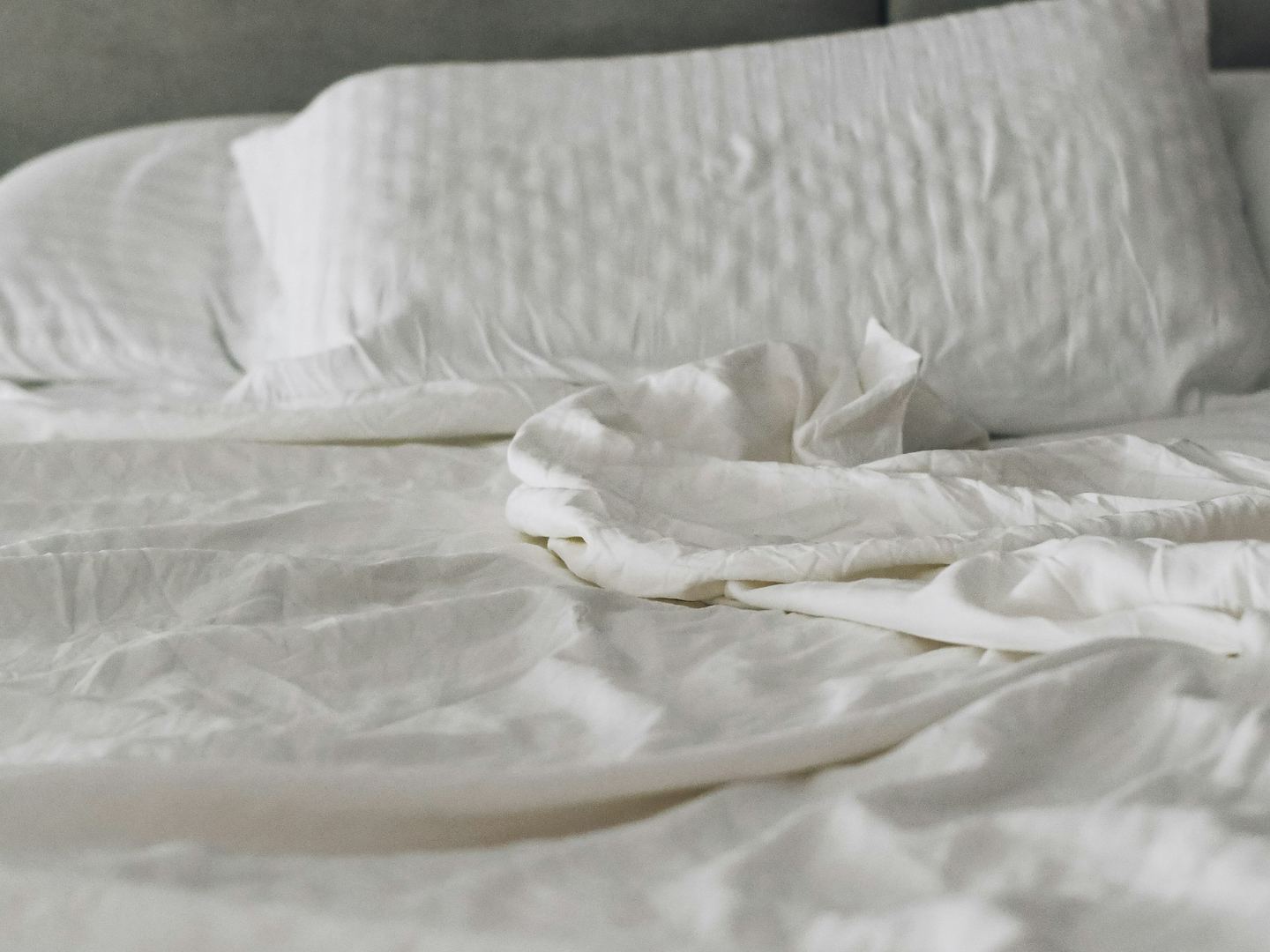 A neatly made bed with white linen and two pillows.