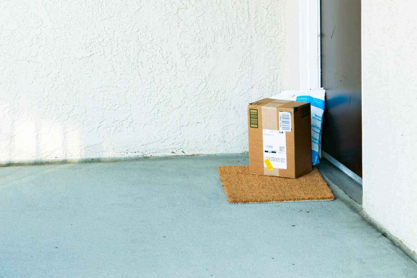 A cardboard box on the doormat of a flat’s front door, in morning light.