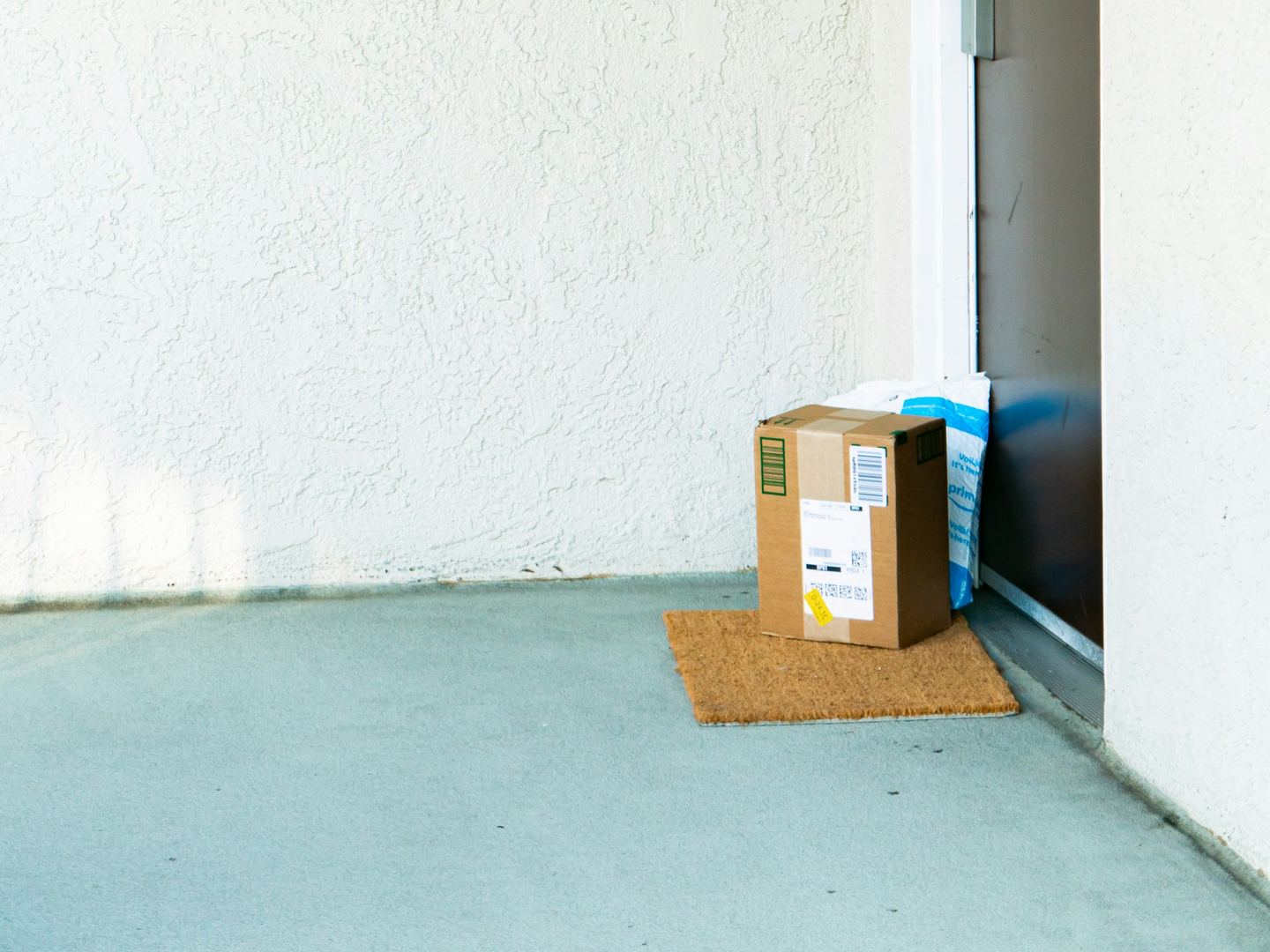 A cardboard box on the doormat of a flat’s front door, in morning light.