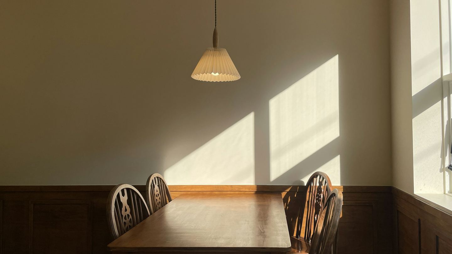 A wooden table and chairs in sunlight.