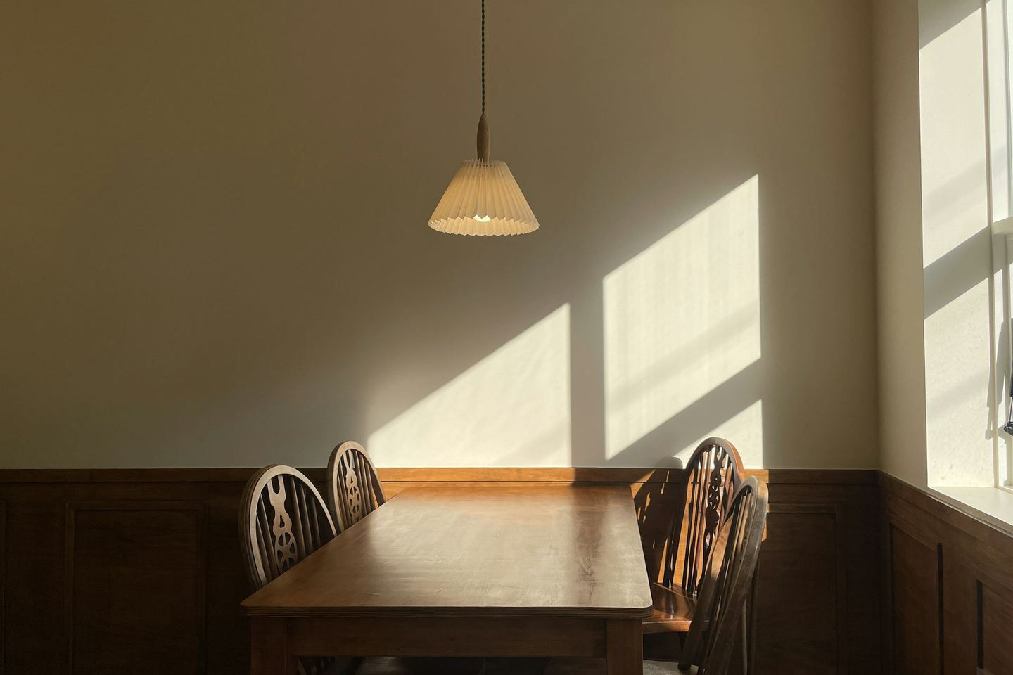 A wooden table and chairs in sunlight.