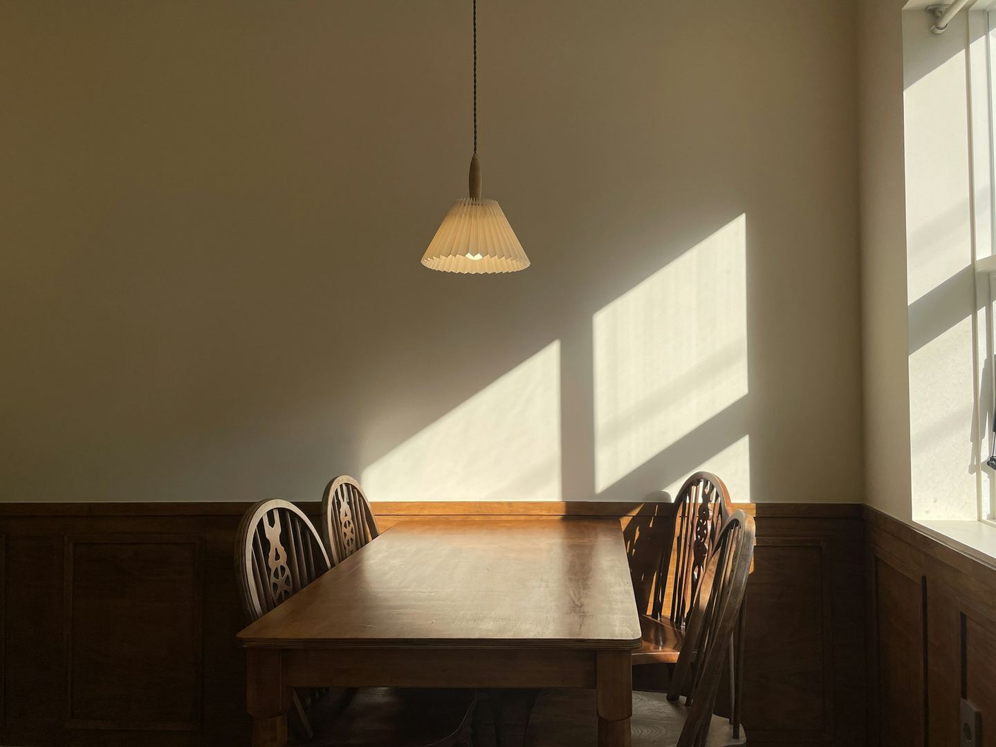 A wooden table and chairs in sunlight.
