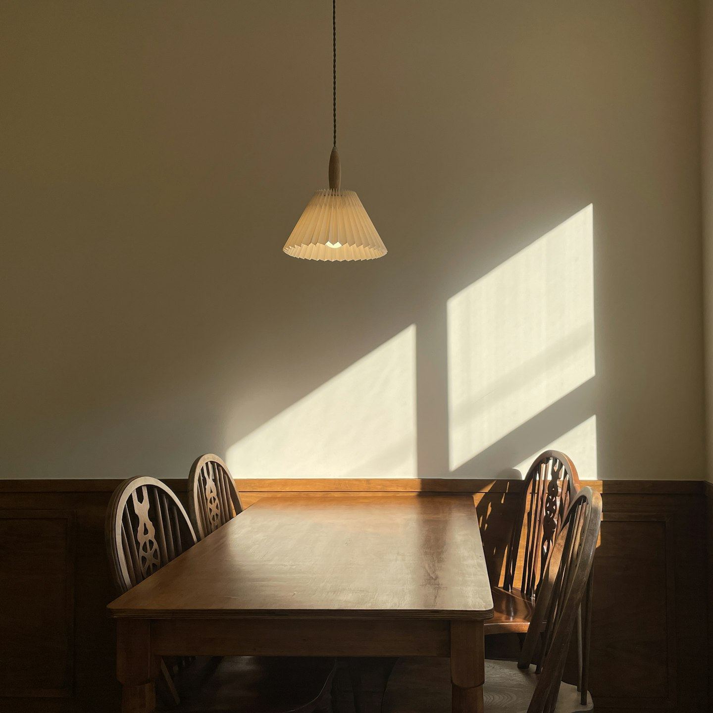 A wooden table and chairs in sunlight.