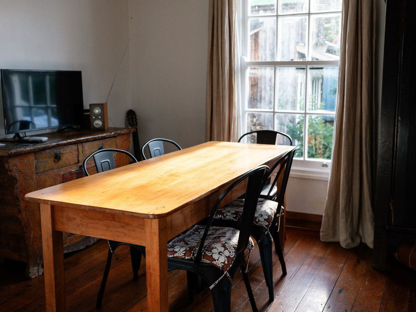 A wooden dining table with chairs near a window.