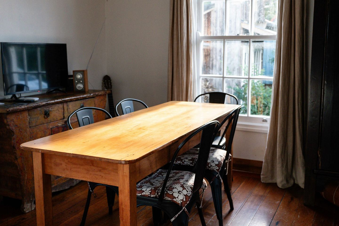 A wooden dining table with chairs near a window.