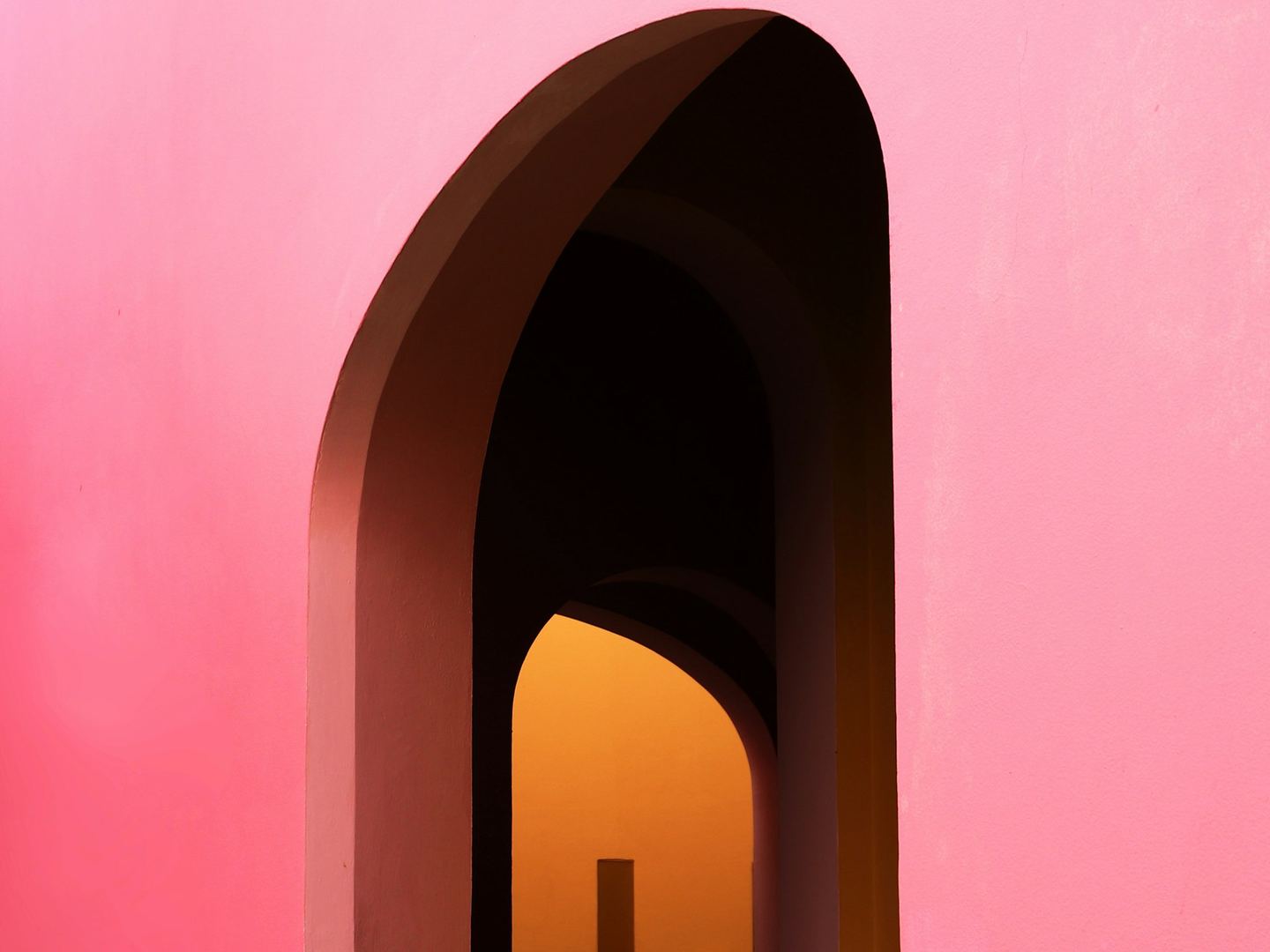 A doorway in a coloured wall with light at the end.