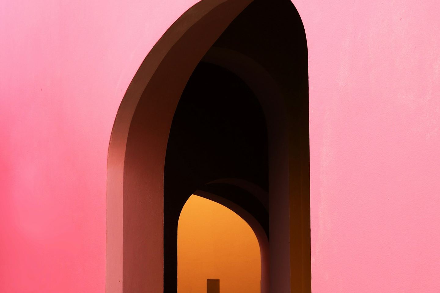 A doorway in a coloured wall with light at the end.