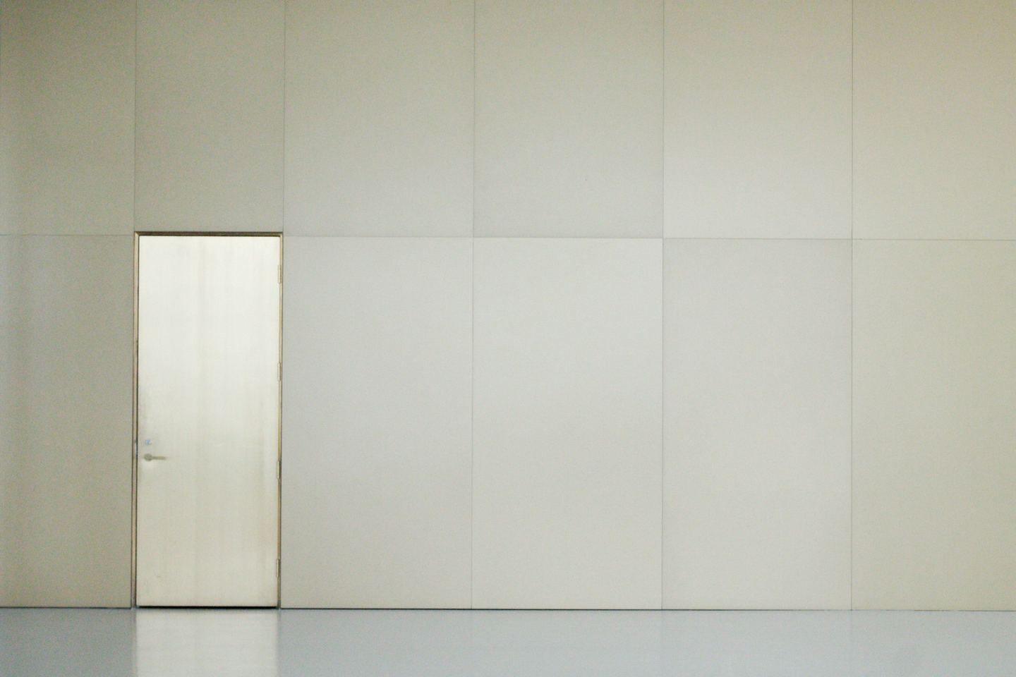 An empty room with a door and a white wall.