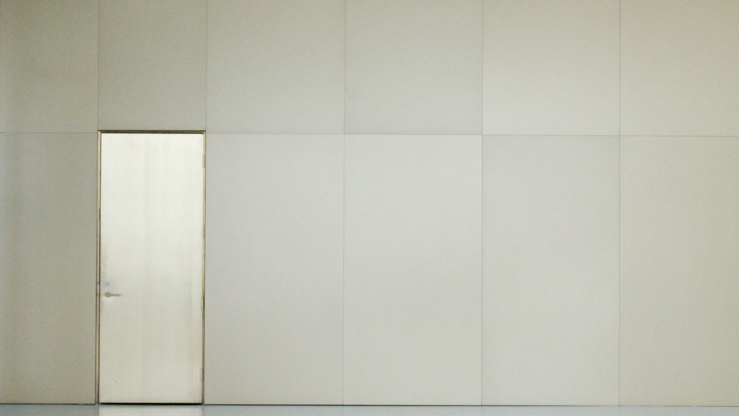An empty room with a door and a white wall.
