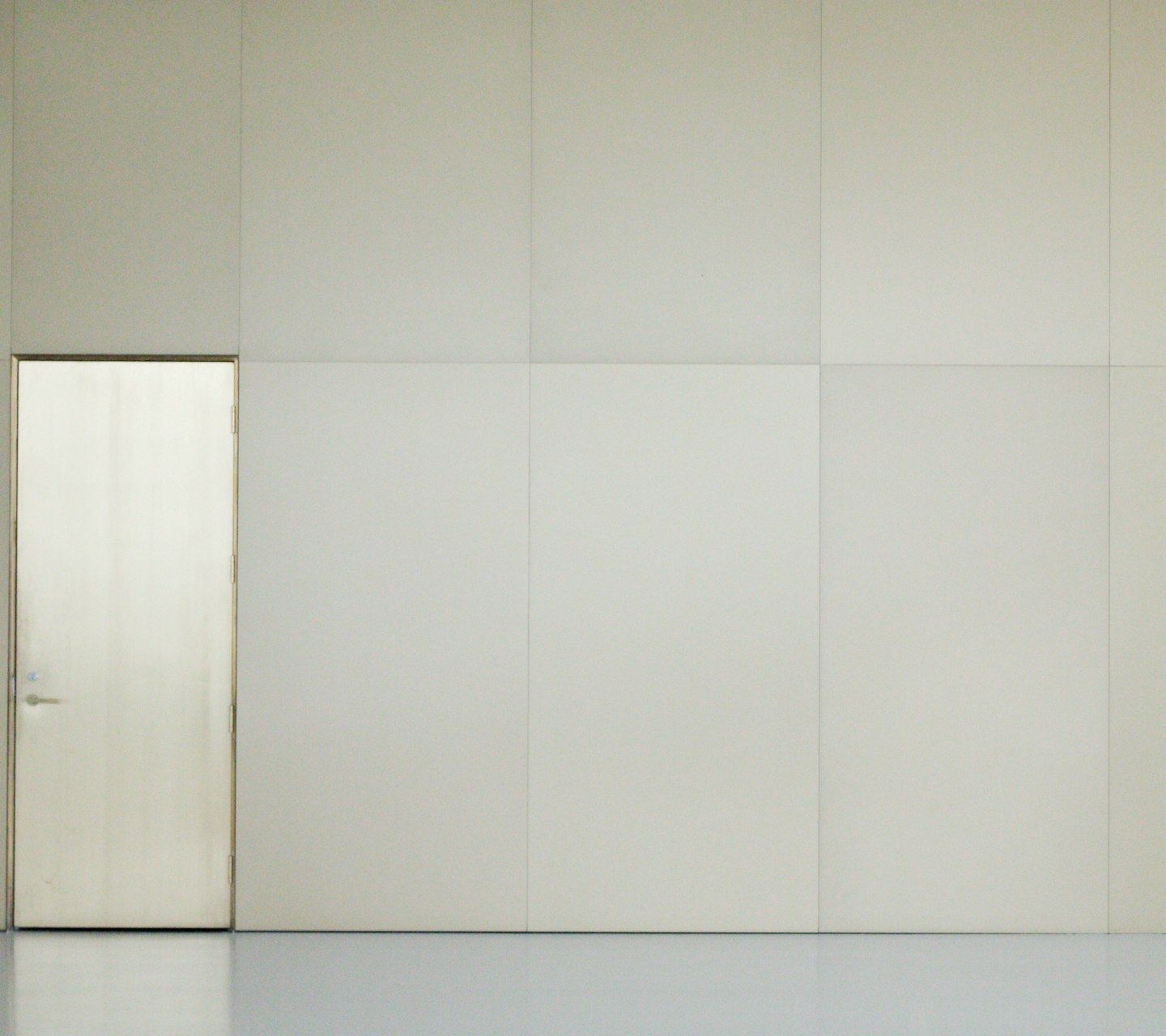 An empty room with a door and a white wall.