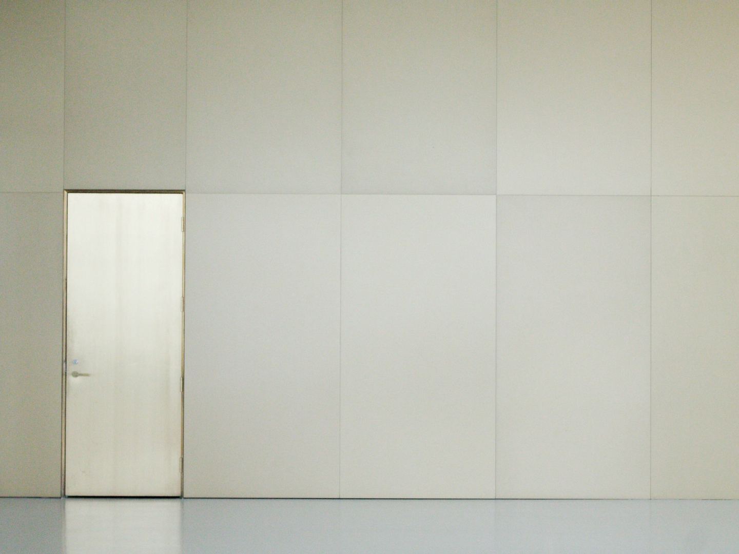 An empty room with a door and a white wall.