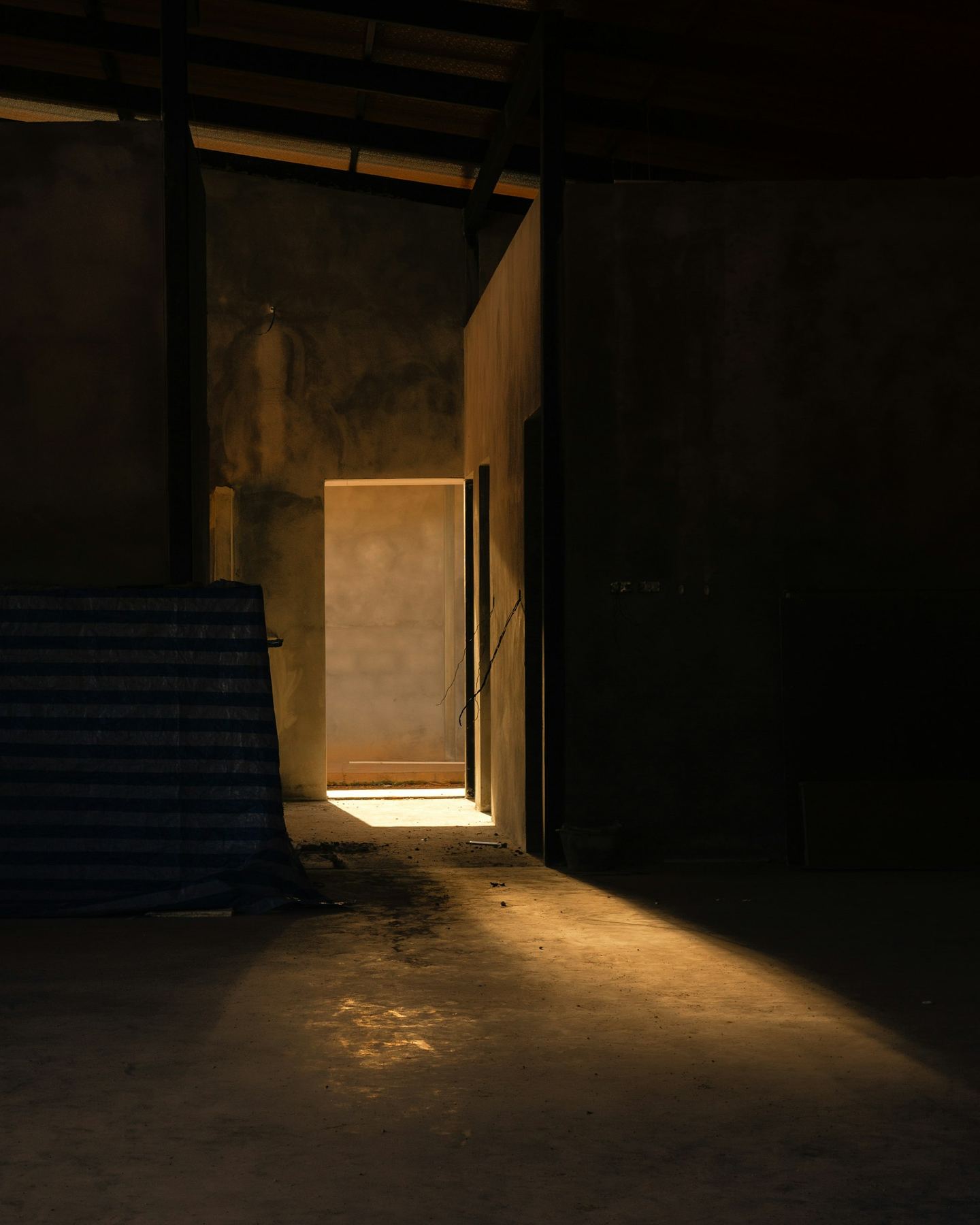 A doorway casting a long beam of warm light across concrete.