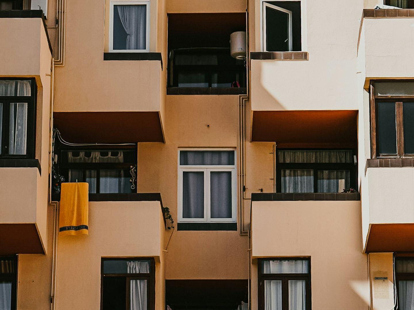 The balconies and windows of a block of flats in afternoon sun.