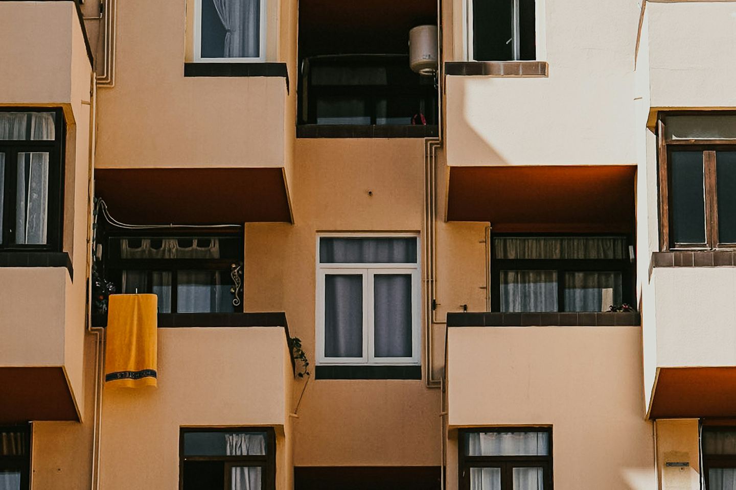 The balconies and windows of a block of flats in afternoon sun.