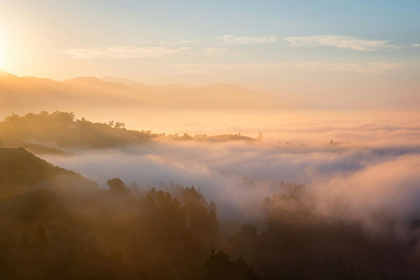 Golden dawn light over ranges of misty mountains, one behind another.