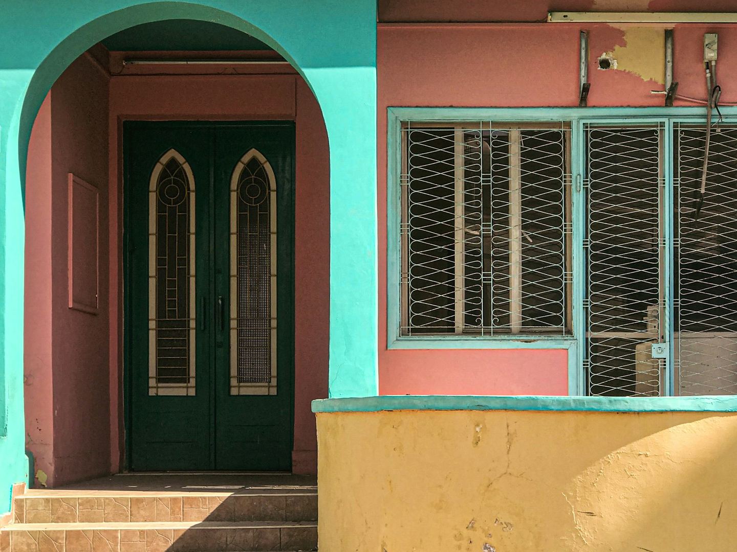 A house painted pink, turquoise and yellow with a green door.
