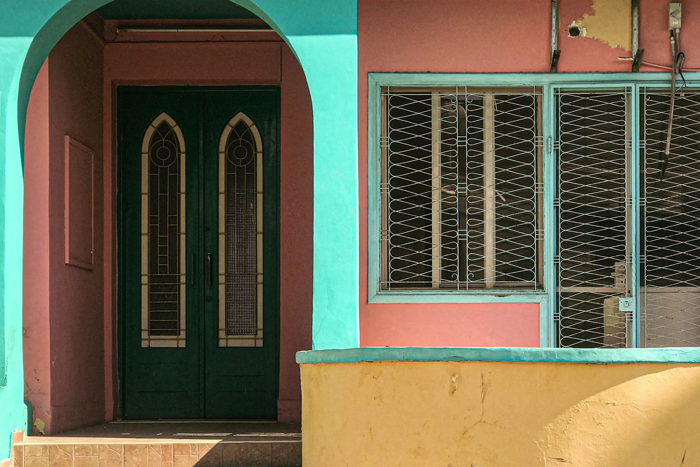 A house painted pink, turquoise and yellow with a green door.
