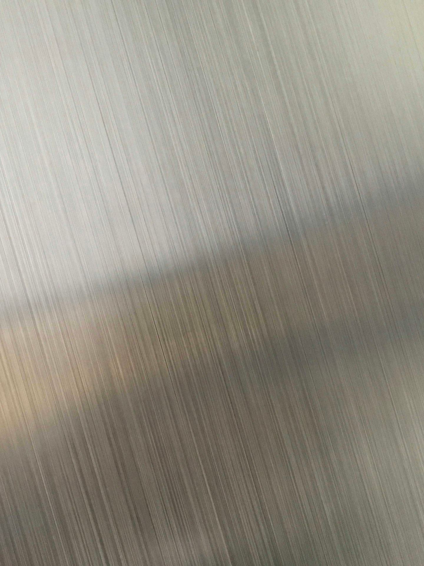 Brushed metal with fine vertical lines and a diagonal reflection.
