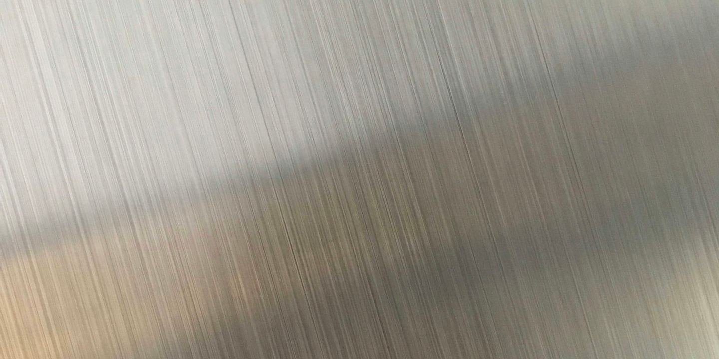 Brushed metal with fine vertical lines and a diagonal reflection.