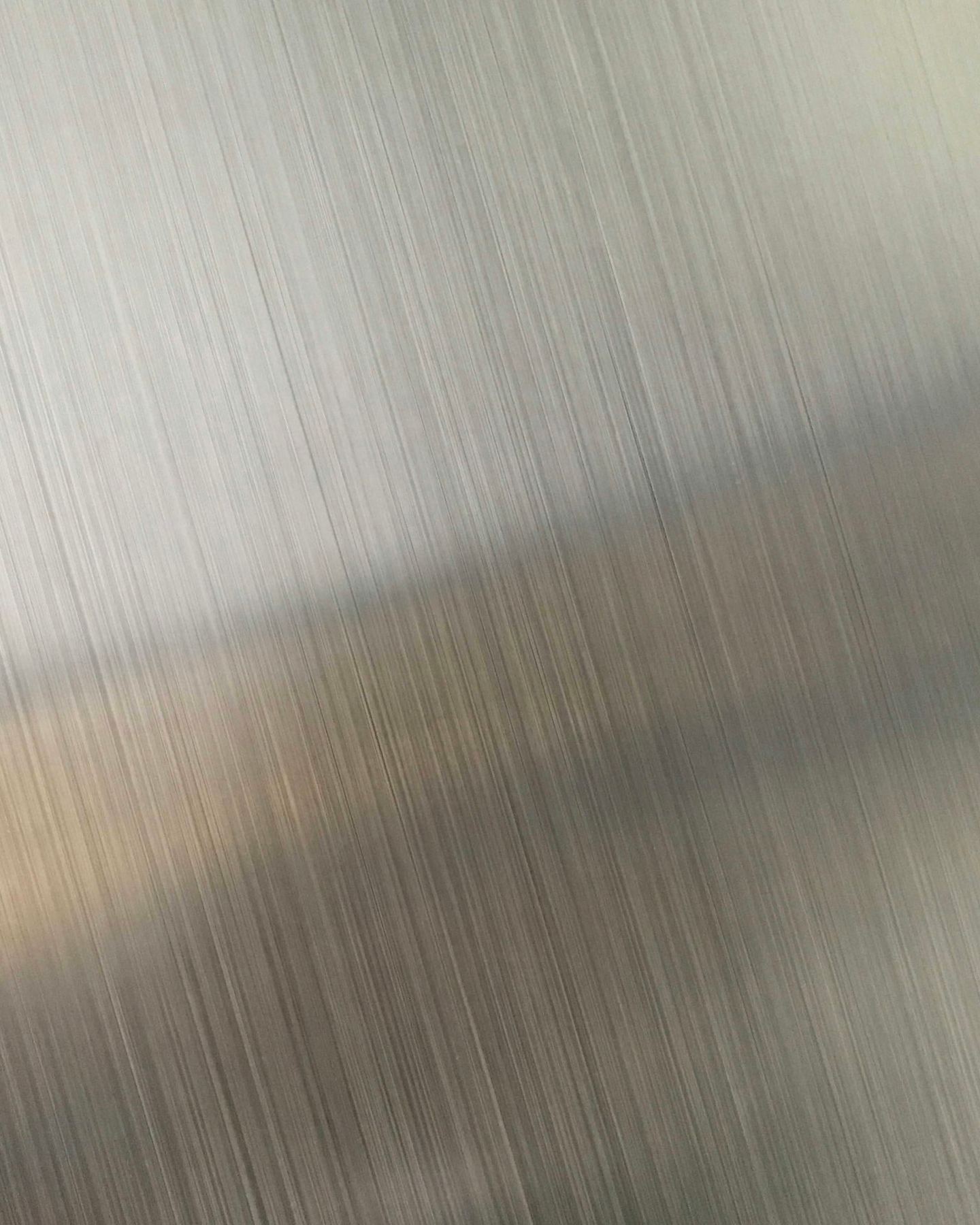 Brushed metal with fine vertical lines and a diagonal reflection.