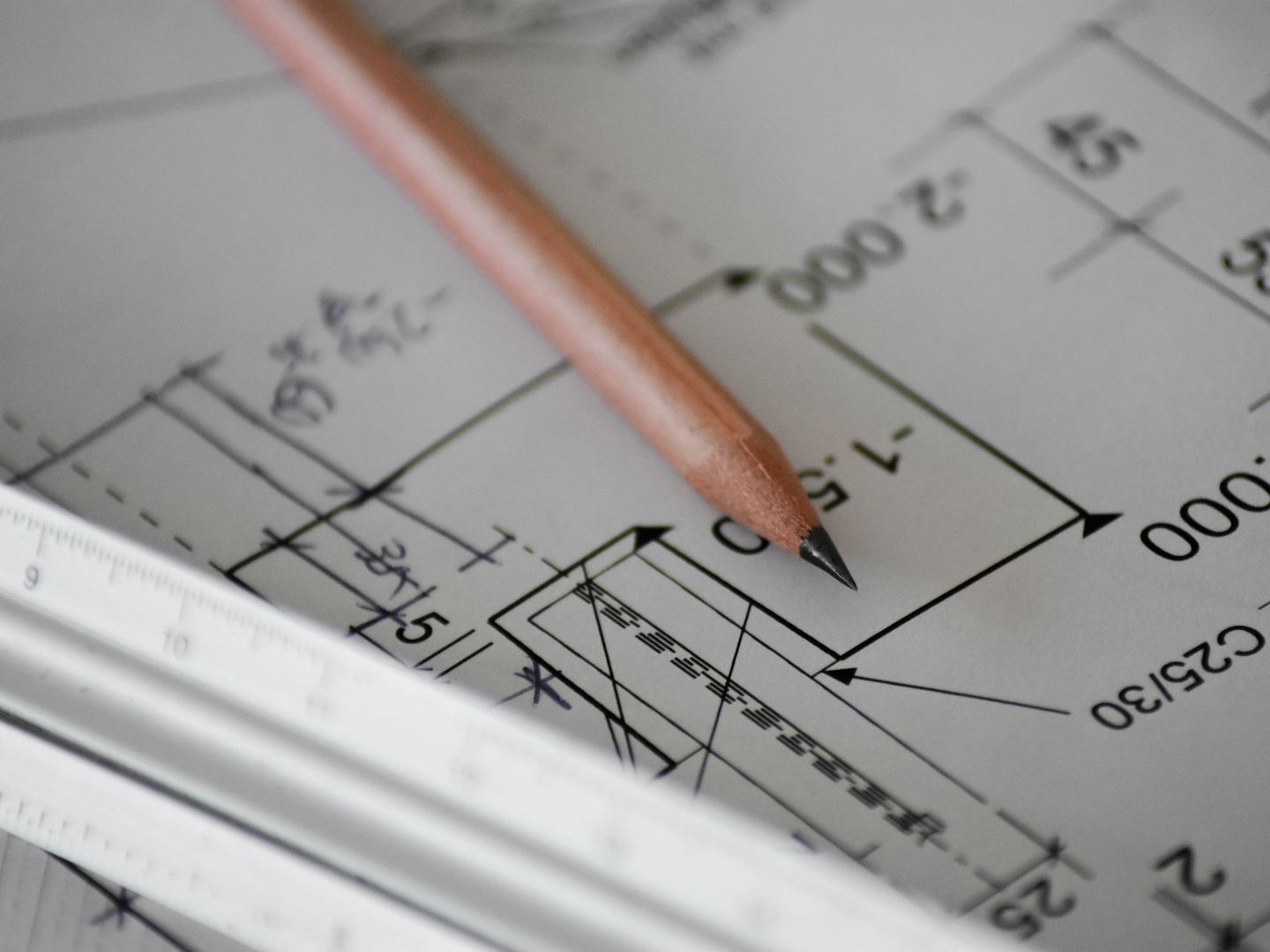 A pencil and a scale rule lying on a dimensioned drawing.