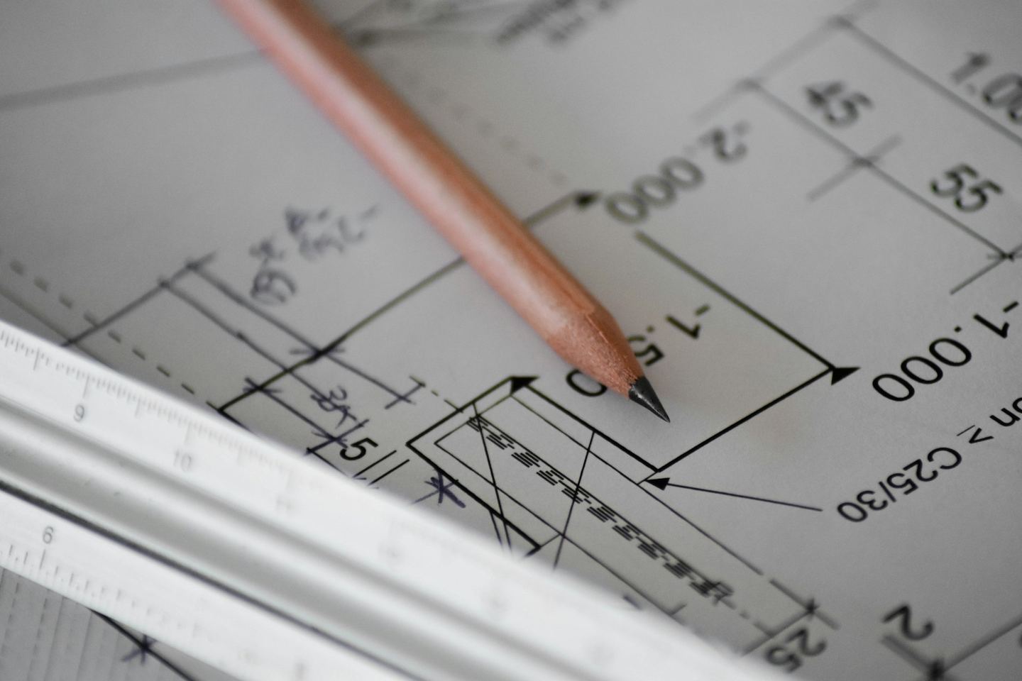 A pencil and a scale rule lying on a dimensioned drawing.