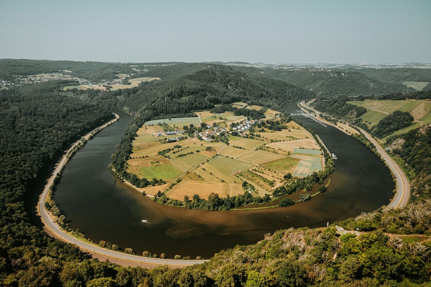 A river in a horseshoe bend with a village and its fields in the belly of the curve, seen from above.