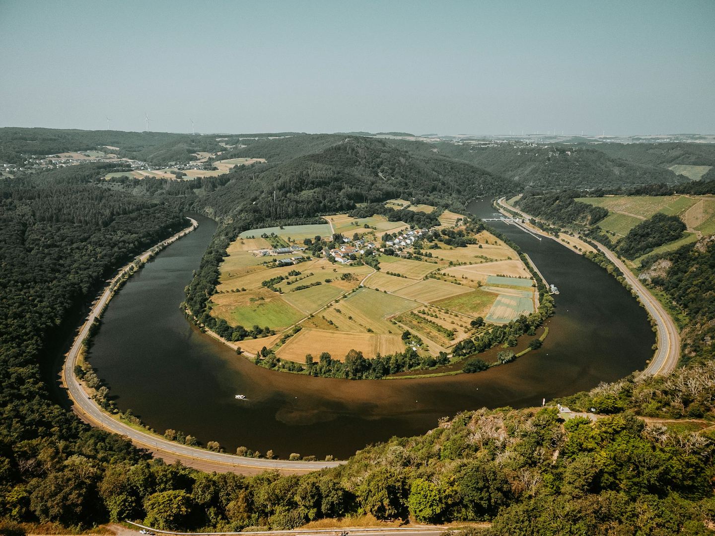 A river in a horseshoe bend with a village and its fields in the belly of the curve, seen from above.