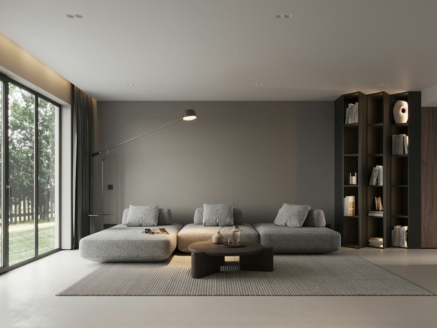 A low grey sofa in the middle of a large living room with a glass wall on one side.