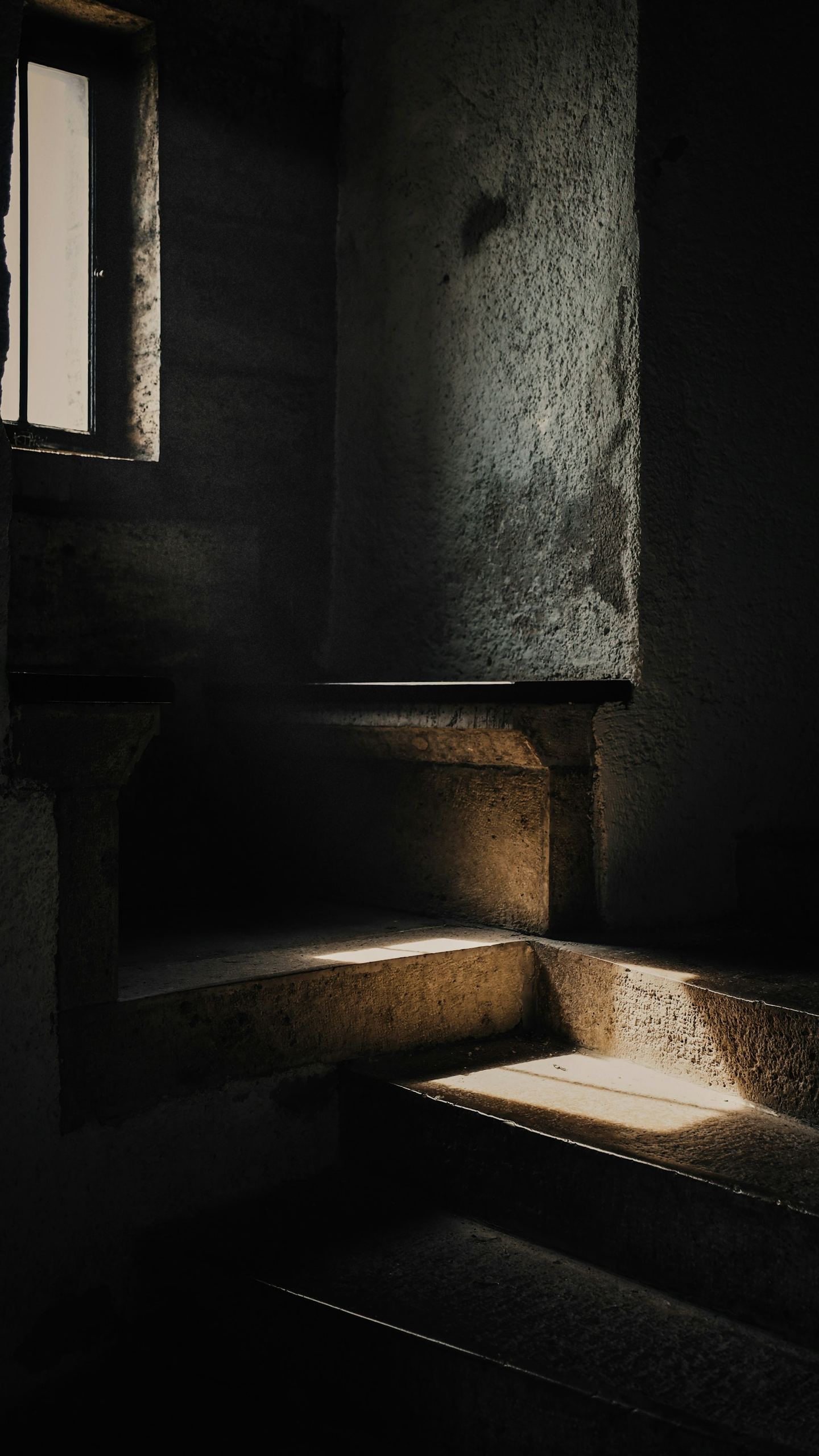 A dark room with stairs and a window.