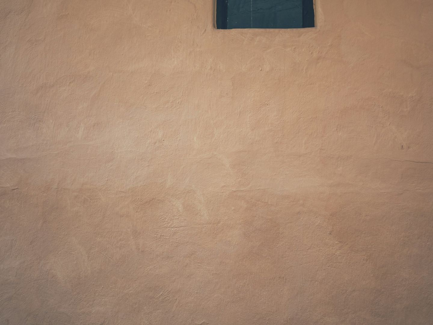 A small square window in a textured wall.