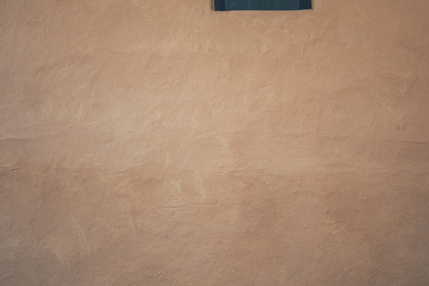 A small square window in a textured wall.